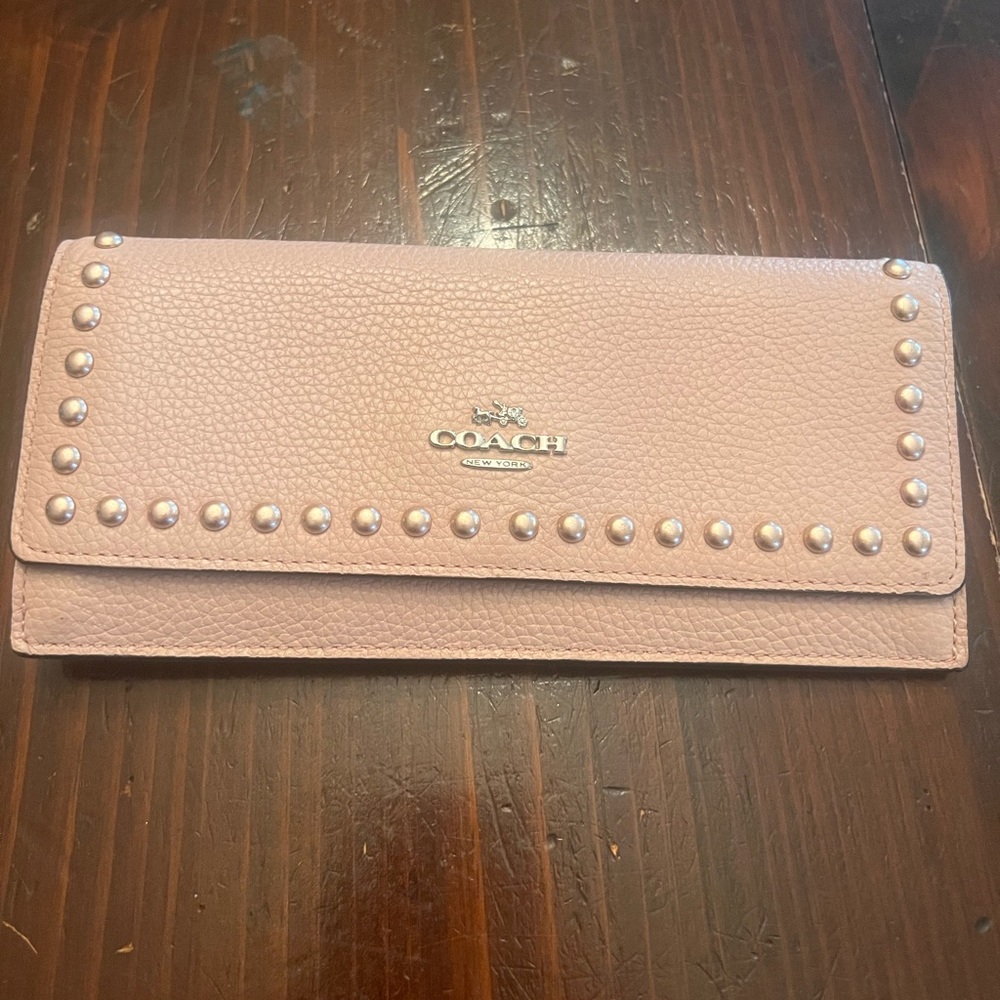 Light pink Coach wallet with gold button looking shapes bordering the front.